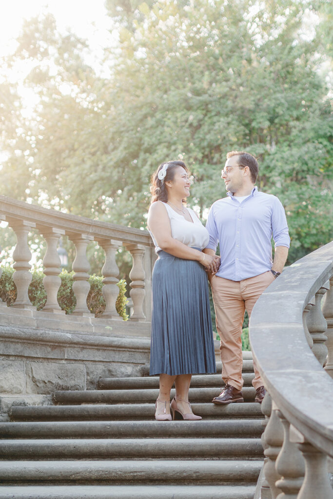 Engaged couple standing on the stone staircase at Greystone Mansion during their engagement session in Beverly Hills, bathed in soft golden light.