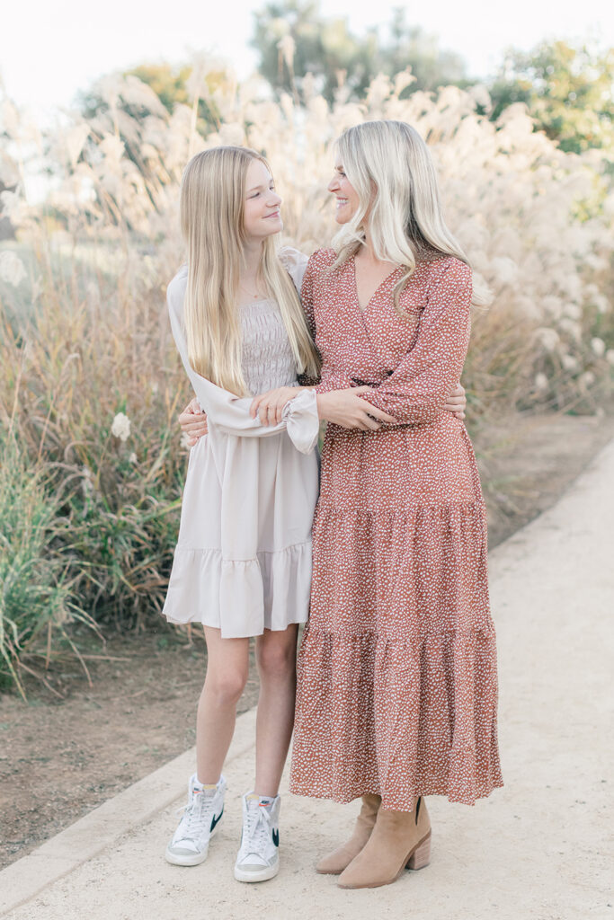 Mom and her school-age daughter sharing a sweet moment during a light and airy family photography session at Encinitas Community Park in San Diego