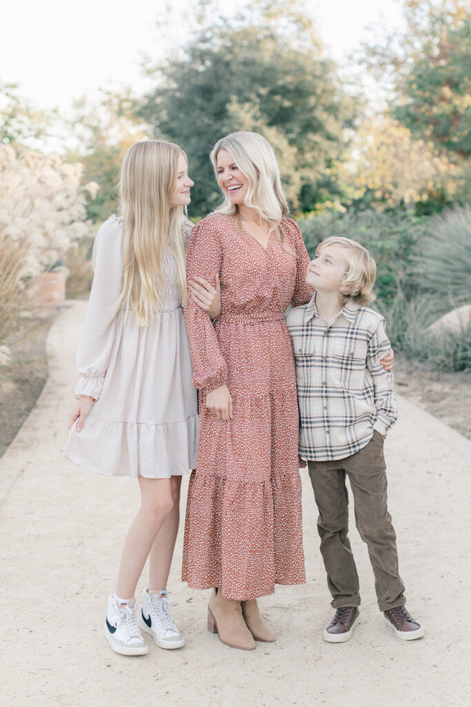 Mother smiling with her two children during a soft and light-filled family photo session at Encinitas Community Park in San Diego