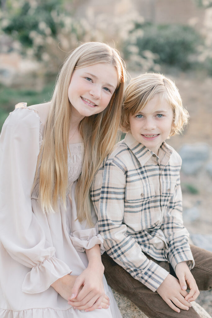 Brother and sister sitting together during a soft and natural light family photo session at Encinitas Community Park in San Diego