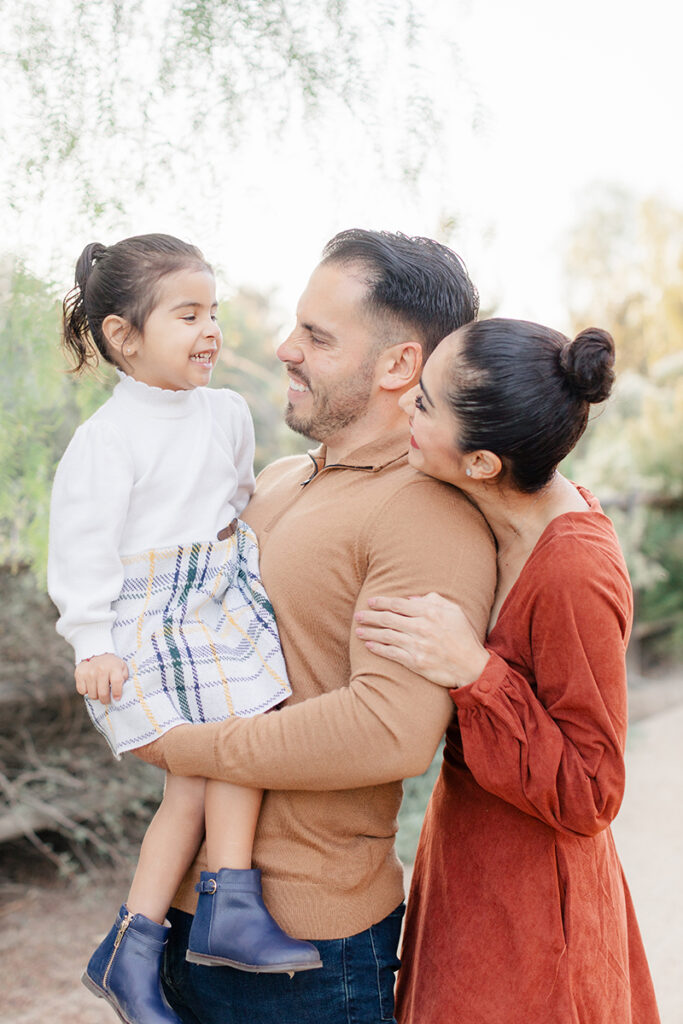 miling family sharing a candid moment during their Montevalle Park photoshoot in Chula Vista, with dad holding daughter and mom