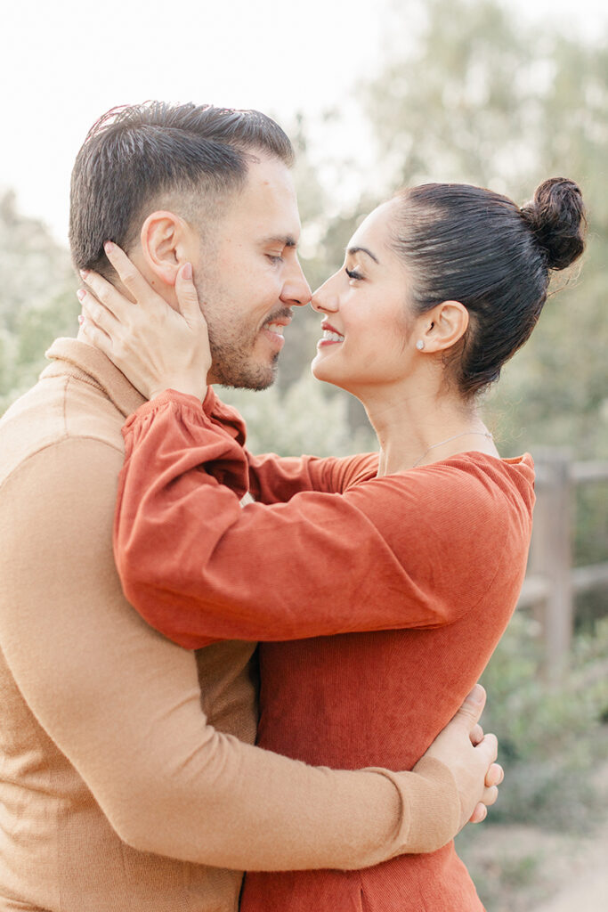 Couple sharing a sweet, romantic moment during a family photoshoot at Montevalle Park in Chula Vista, dressed in coordinating fall tones