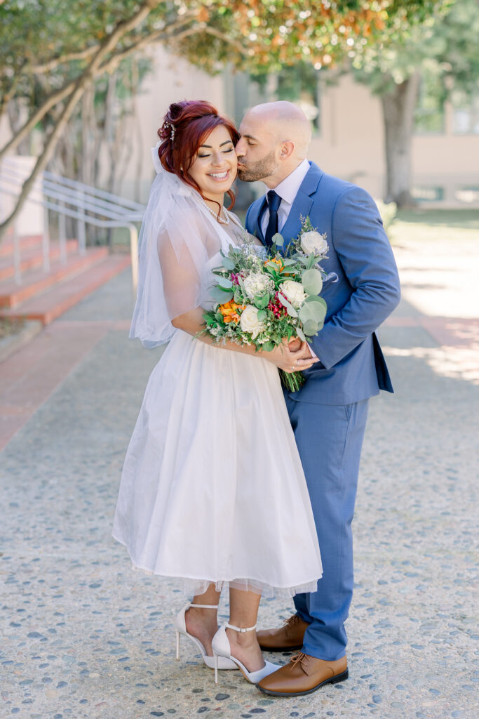 groom kissing bride on the cheek during san diego courthouse wedding